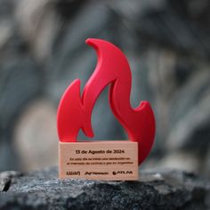 a red sculpture sitting on top of a rock next to a wooden plaque that reads 15 de agonto de 2020