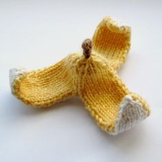 a knitted banana is sitting on a white counter top, with the bottom part partially covered in yarn