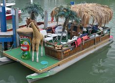 a fake giraffe is standing on the back of a boat in the water