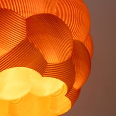 an orange lamp hanging from the ceiling in front of a gray wall with white and yellow circles on it