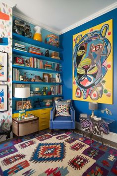 a brightly colored living room with blue walls and colorful rugs on the floor,