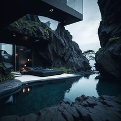 an outdoor swimming pool surrounded by rocks and greenery with a glass balcony above it