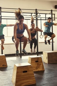 a group of people doing exercises in a crossfit gym with wooden boxes on the floor