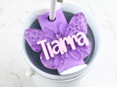 a purple flower with the word amai on it sitting in a cup next to a toothbrush