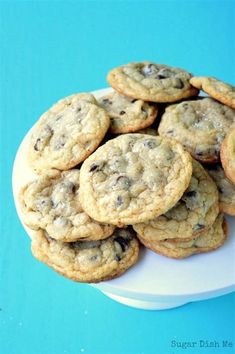 chocolate chip cookies stacked on top of each other in a white plate against a blue background