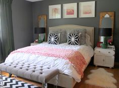 a bedroom with gray walls, white bedding and black and white rugs on the floor