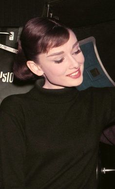 a woman sitting in a chair with her hand on the back of her shoulder and smiling