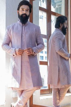 a man standing in front of a mirror wearing a pink sherwa with white pants