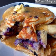 pancakes with blueberries and butter are stacked on top of each other in a white plate