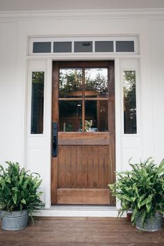 two potted plants are sitting on the front step of a house with a wooden door