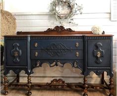 an ornately decorated sideboard with two drawers and one drawer on the top, in front of a white wall