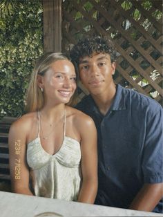 a young man and woman are sitting at a table smiling for the camera while posing for a photo