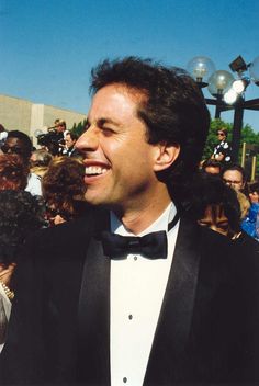 a man in a tuxedo smiles as he stands next to a group of people