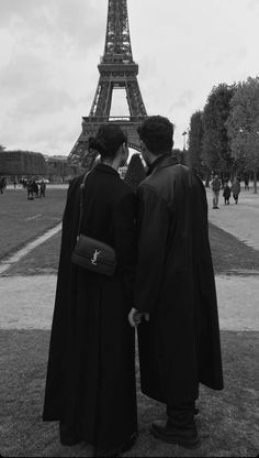 two people standing next to each other in front of the eiffel tower, paris