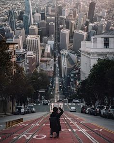 a person taking a photo on a city street with buildings in the background and cars driving down the road