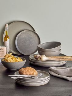 a table topped with plates and bowls filled with food next to a bottle of wine