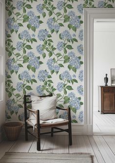 a chair sitting in front of a wall with blue flowers on it