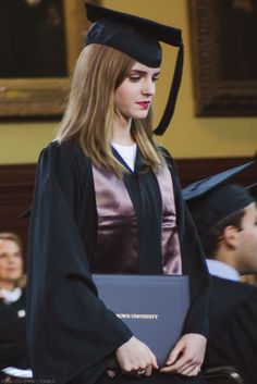 a woman standing in front of other people wearing graduation gowns