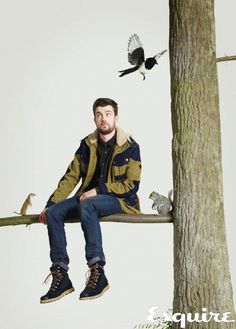 a man sitting on top of a tree branch next to a bird flying over him