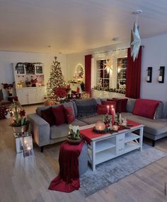 a living room decorated for christmas with red and grey furniture, candles and decorations on the coffee table