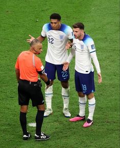 two soccer players talking to an official on the field