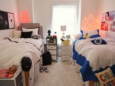 two twin beds in a bedroom with white walls and carpeted flooring next to windows