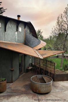 an outdoor area with a large metal tub in the foreground and a house on the other side