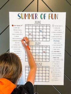 a young child writing on a summer of fun calendar