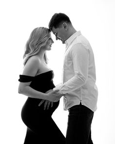 a pregnant man and woman standing next to each other in black and white with their hands on the belly