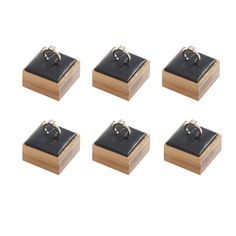 four rings are sitting on top of a wooden box with black leather cover and wood base