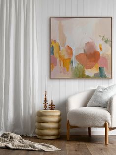 a white chair sitting in front of a painting on the wall next to a window