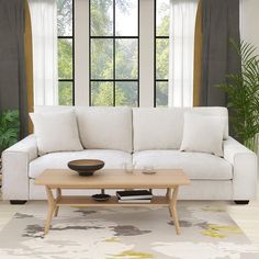 a living room with a couch, coffee table and large windows in the back ground