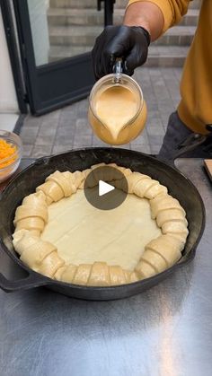 a person pouring batter into a pan with food in it