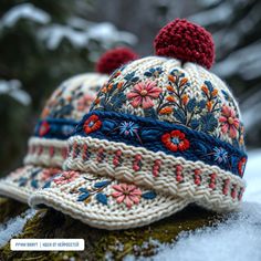 a knitted hat with pom - poms on top of snow covered ground