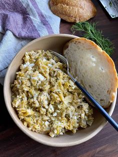 a bowl filled with food next to a loaf of bread