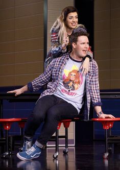 a man sitting on top of a table next to a woman with her arm around him