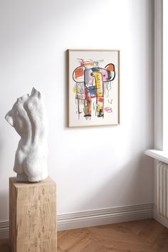 a white sculpture sitting on top of a wooden block in front of a wall mounted art piece