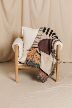 a chair with a blanket on top of it sitting in front of a white wall