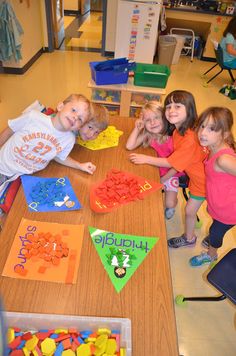 several children are gathered around a table with toys