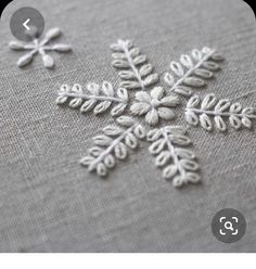 an embroidered snowflake is shown on a piece of linen