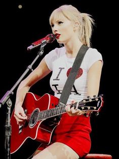 a woman with a guitar on stage at a concert