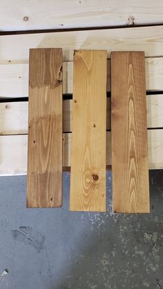 three pieces of wood sitting on top of a wooden pallet next to a wall