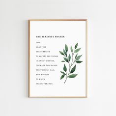 the serenity prayer print with green leaves on white paper in a wooden frame hanging on a wall