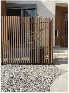 a wooden fence in front of a house with gravel on the ground next to it