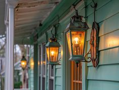 two lights are hanging from the side of a house next to a porch with blue siding