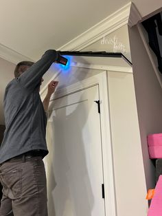 a man is painting the trim on a white door with blue light coming from it