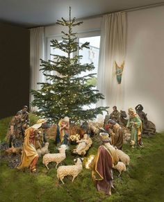 the nativity scene is displayed in front of a christmas tree with figurines