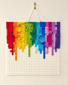 a wall hanging made out of legos with different colored parts on it and a button in the middle