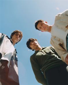 three men standing next to each other looking up at the sky