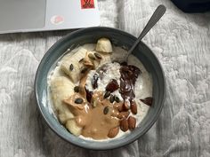 a bowl of oatmeal with bananas, nuts and chocolate in front of a laptop